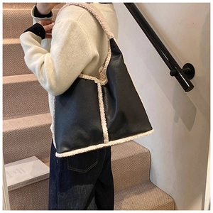 Detail of vintage tote bag with black pebbled leather and white faux fur trim on stairs