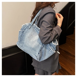 Detail view of large washed denim tote with frayed edges and side pocket design