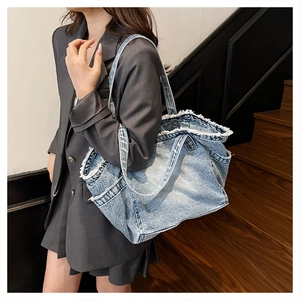 Detail of blue washed denim tote bag showing trendy fringe edges and spacious shoulder strap