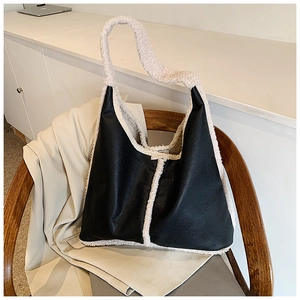 Detail of hobo bag in black lychee leather with white faux shearling trim on a chair