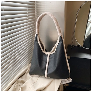 Detail of black pebbled leather tote with beige faux shearling trim and wide shoulder strap