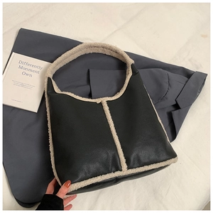 Detailed shot of black pebbled leather and plush faux shearling trim on a chic tote bag