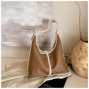 Close-up of brown leather and white faux shearling shoulder bag in a warm winter setting