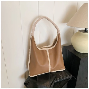 Detail of brown leather and cream faux fur hobo bag on a decorative indoor pedestal
