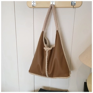 Detail of caramel leather and beige faux fur patchwork dumpling bag hanging on a hook