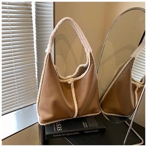 Close-up of retro brown leather tote with white plush trim detail on a black book