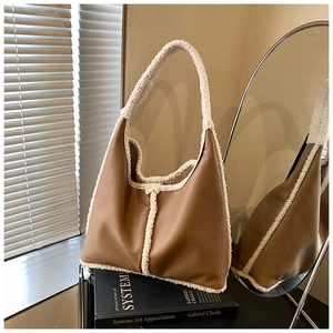 Detail of brown pebbled leather hobo bag with thick faux fur trim on artistic book