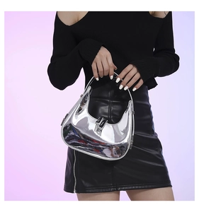 Silver mirror half-moon handbag shown with model in stylish black outfit and purple background