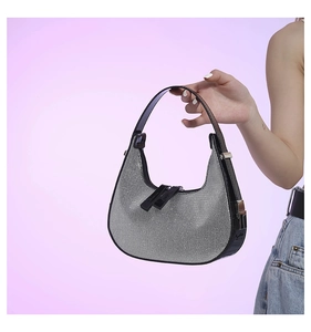 Close-up of sparkling silver rhinestone handbag with black leather trim and zipper detail