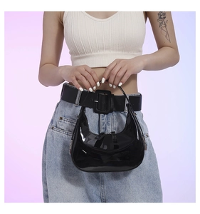 Close-up of black patent leather crescent shoulder bag with glossy finish on model