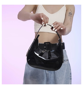Close-up of shiny black patent leather crescent moon bag with silver hardware and zipper