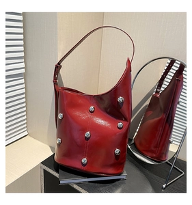 Detail of glossy red shoulder bag with silver studs and mirror reflection showing texture