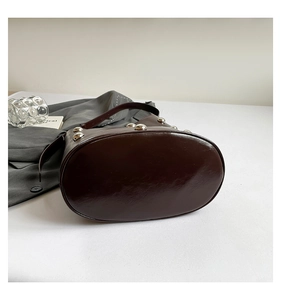 Detailed view of dark brown patent leather shoulder bag featuring silver stud ornaments