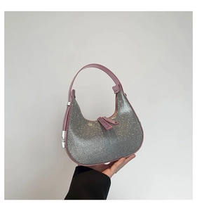 Close-up of sparkling silver rhinestone crescent bag with pink leather trim and dual zippers