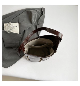 Detail view of large dark brown bucket bag interior with silver rivets and fabric lining