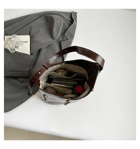 Deep brown glossy leather bucket bag with silver studs showing spacious interior capacity
