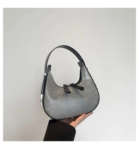 Macro detail of silver rhinestones and black leather trim on a hobo moon bag