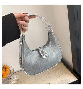 Close-up of sparkling silver rhinestone crescent bag with white leather handle details