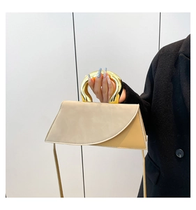 Detail of elegant two-tone geometric handbag featuring a bold gold circular metal handle