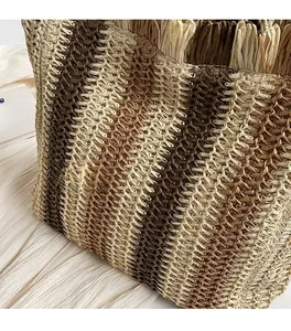 Close-up of the striped handmade woven straw tote showing detailed texture and fringe trim