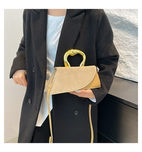 Detail of creative U-shaped gold handle and beige suede texture on structured handbag