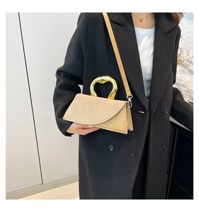 Detail of beige square handbag with gold heart-shaped handle styled on black coat