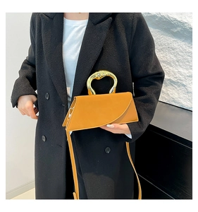 Detail of ginger yellow geometric handbag featuring a gold ring handle on a black coat