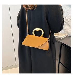 Detail of mustard yellow geometric leather handbag with gold metal U-shaped handle