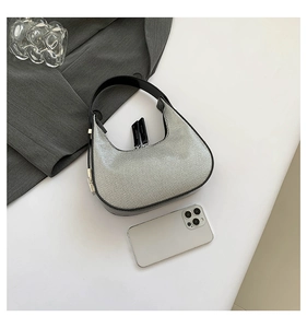 Detailed close-up of a silver rhinestone crescent bag with phone for size reference