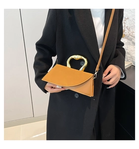 Close-up of mustard yellow leather handbag with heart-shaped gold metal handle and strap