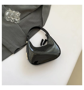 Detail of glossy black patent leather crescent hobo bag with silver metallic hardware