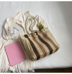 Macro shot of striped woven straw tote bag with fringe edge and rope handles on white dress