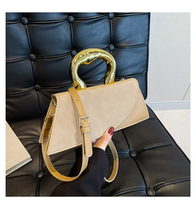 Detailed view of apricot square bag with unique artistic gold metallic handle