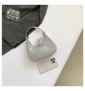 Top view of shiny silver sequin crescent underarm bag with suit and fashion accessories