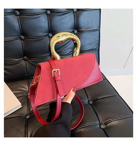 Detailed close-up of a red leather crossbody bag with a unique gold metal ring handle