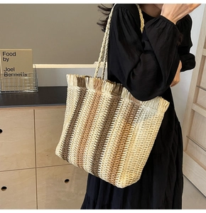 Detail shot of a large striped straw tote bag with fringe edge and braided handles