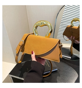 Detail of elegant brown leather square handbag with golden organic wave-shaped handle