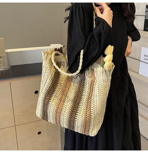Macro view of woven straw tote bag featuring brown gradient stripes and tassel fringe detail