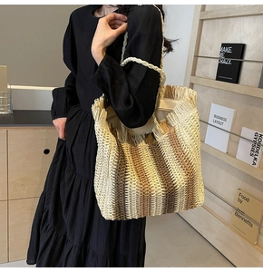 Detail of woven straw tote bag featuring brown stripes and decorative fringe trim