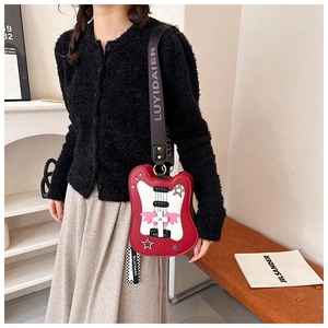 Detailed view of red guitar-shaped crossbody bag with bat wings and wide woven strap