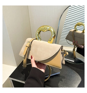 Detail of modern asymmetric handbag with gold ring handle and beige suede leather stitching