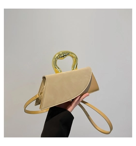 Detail of minimalist beige handbag featuring a distinctive gold metal ring handle