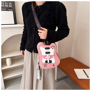 Detail of pink and white guitar shaped crossbody bag with star studs and wing accents