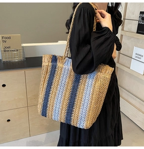 Detail of hand-woven straw tote with blue stripes, fringe trim and large capacity