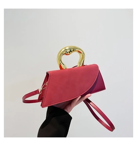 Detail view of fuchsia asymmetrical leather bag with a unique chunky gold metal handle