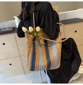 Detail of woven straw tote bag with blue stripes and decorative tassels for summer