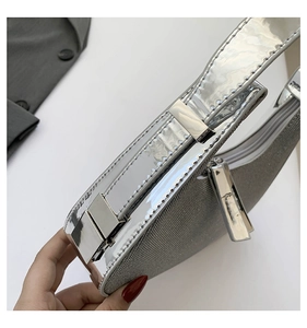 Detail of silver glitter crescent bag featuring glossy PU trim and metallic zipper