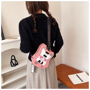 Creative pink guitar-shaped crossbody bag shown on a model with a wide branded shoulder strap