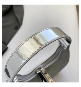 Detailed macro view of the silver mirror finish handle and stitching on the crescent bag