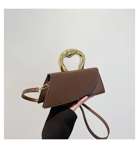 Detail of brown leather handbag featuring unique gold metal handle and asymmetric flap design